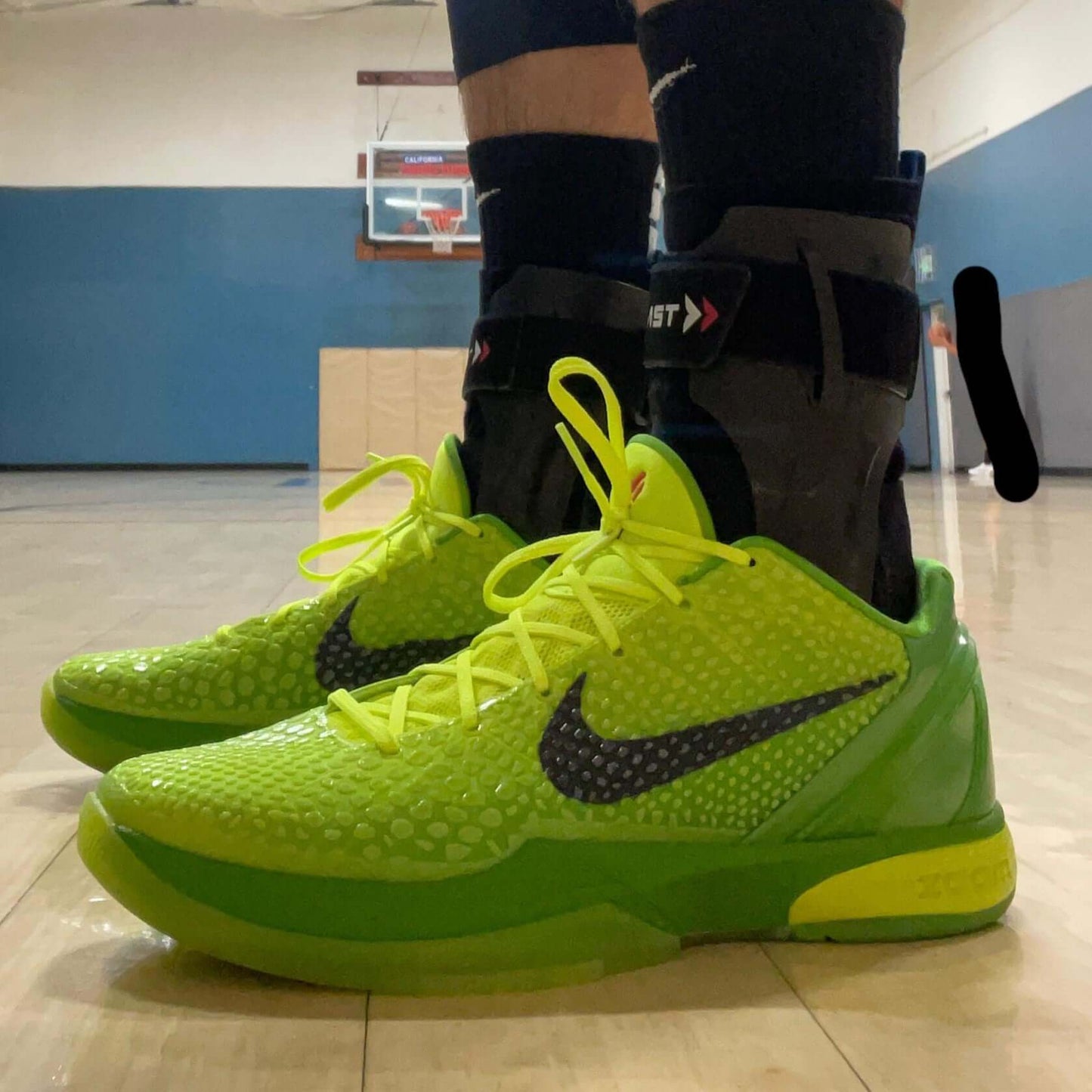 Person wearing bright green Nike basketball shoes on a basketball court.