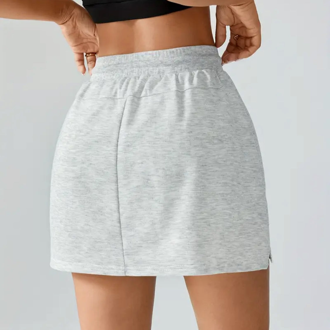 Person wearing a gray skirt on a plain background