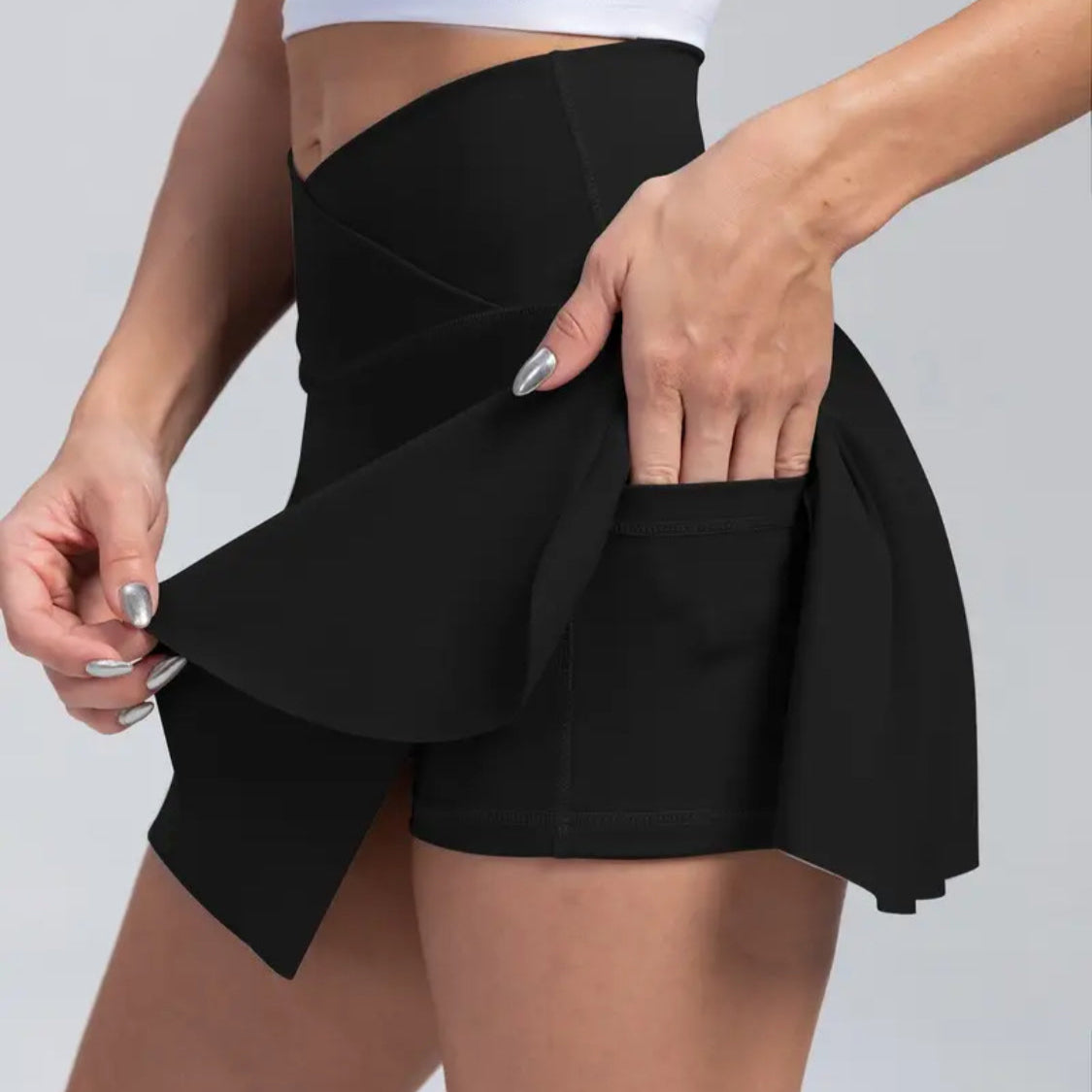 Person wearing a black skirt with a white top on a light gray background