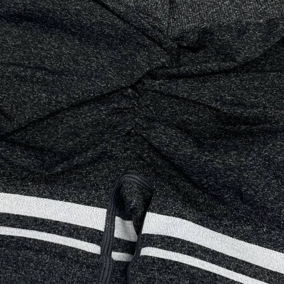 Close-up of a dark gray hoodie with white stripes on the sleeve, worn by a person.