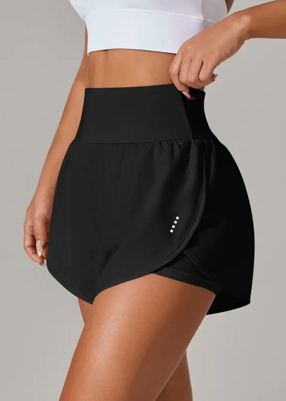 Black high-waisted shorts worn by a person on a gray background