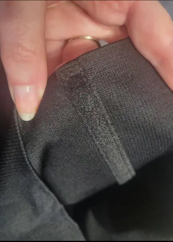 Close-up of a hand holding a dark gray fabric item with a blurred background