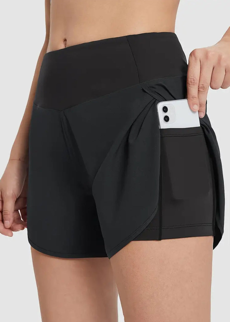 Black athletic shorts with a pocket holding a phone on a white background