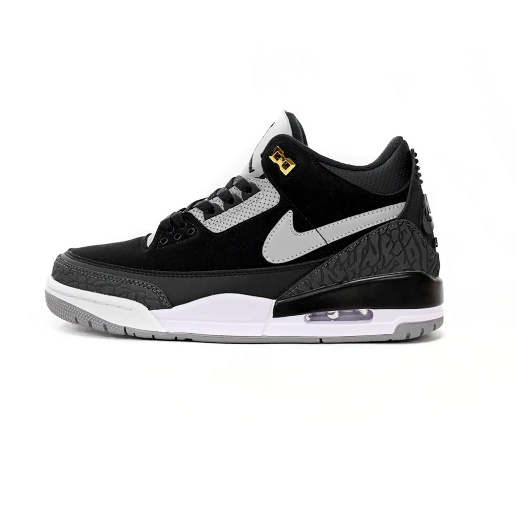 Black and white sneaker with a gold accent on a white background
