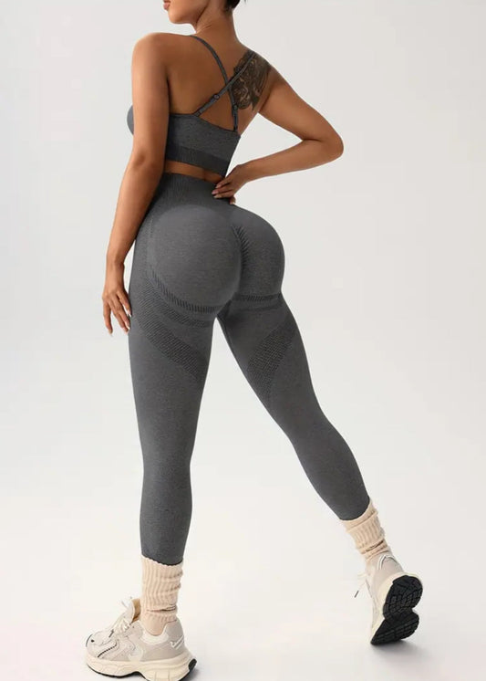 Person wearing gray athletic leggings and sports bra on a white background