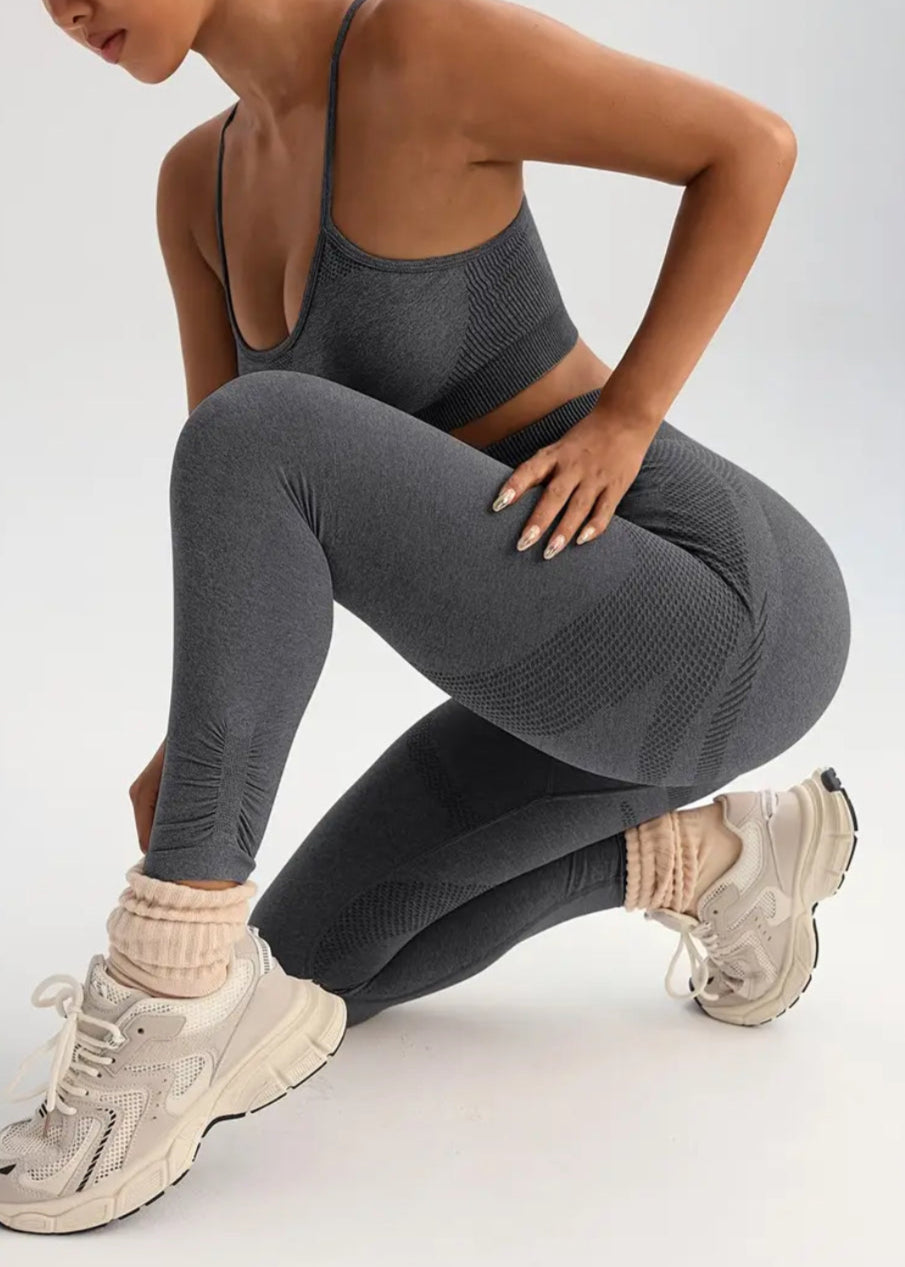 Person wearing gray athletic leggings and sports bra on a white background