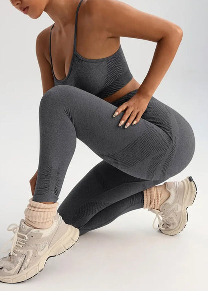 Person wearing gray athletic leggings and sports bra on a white background