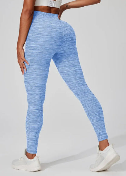 A pair of blue Yoga Space Dye Leggings featuring a high-rise waistband and a no front seam design, modeled by a person posing with one hand on her hip.