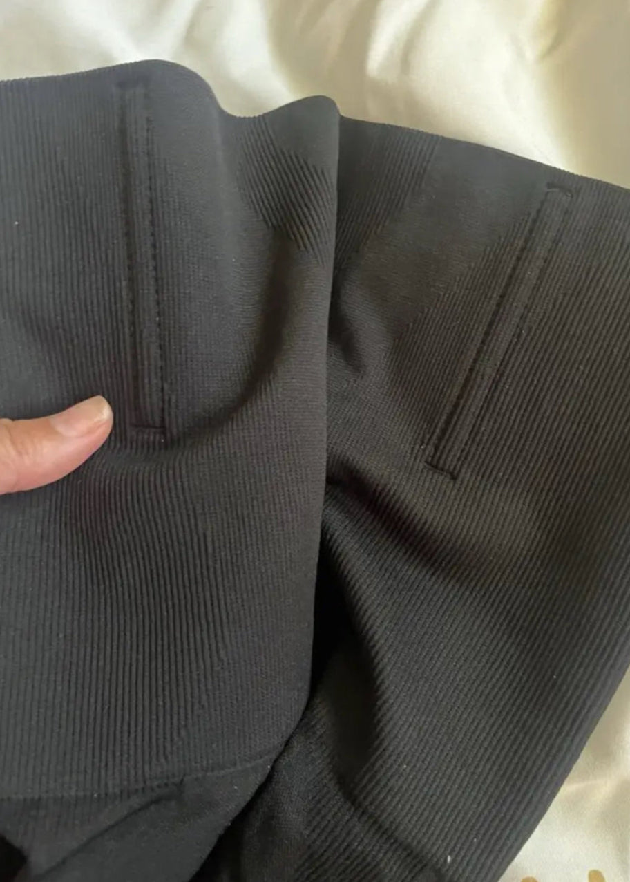 Close-up of dark gray pants with a hand holding the fabric.