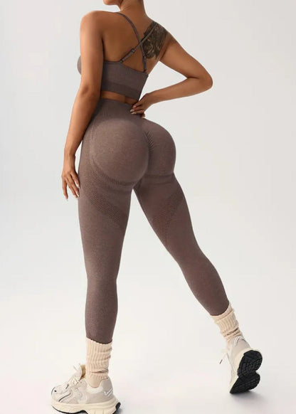 Person wearing brown leggings and sports bra on a white background