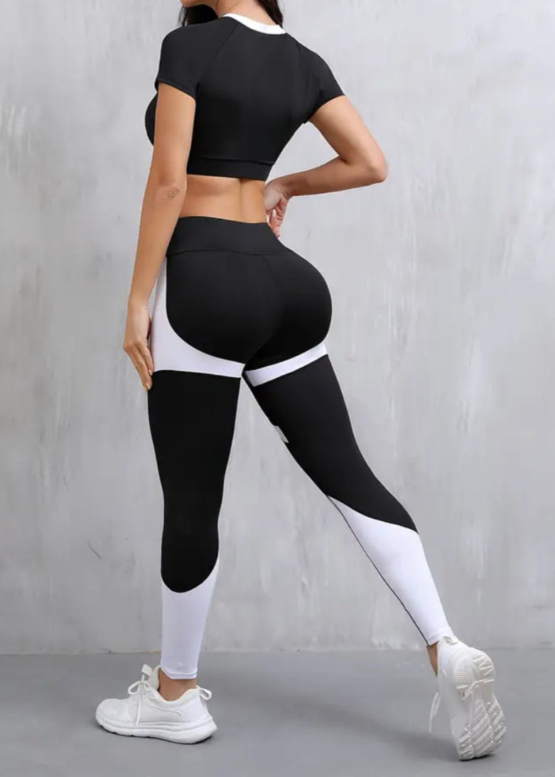 Woman wearing a black athletic outfit with white accents against a gray background