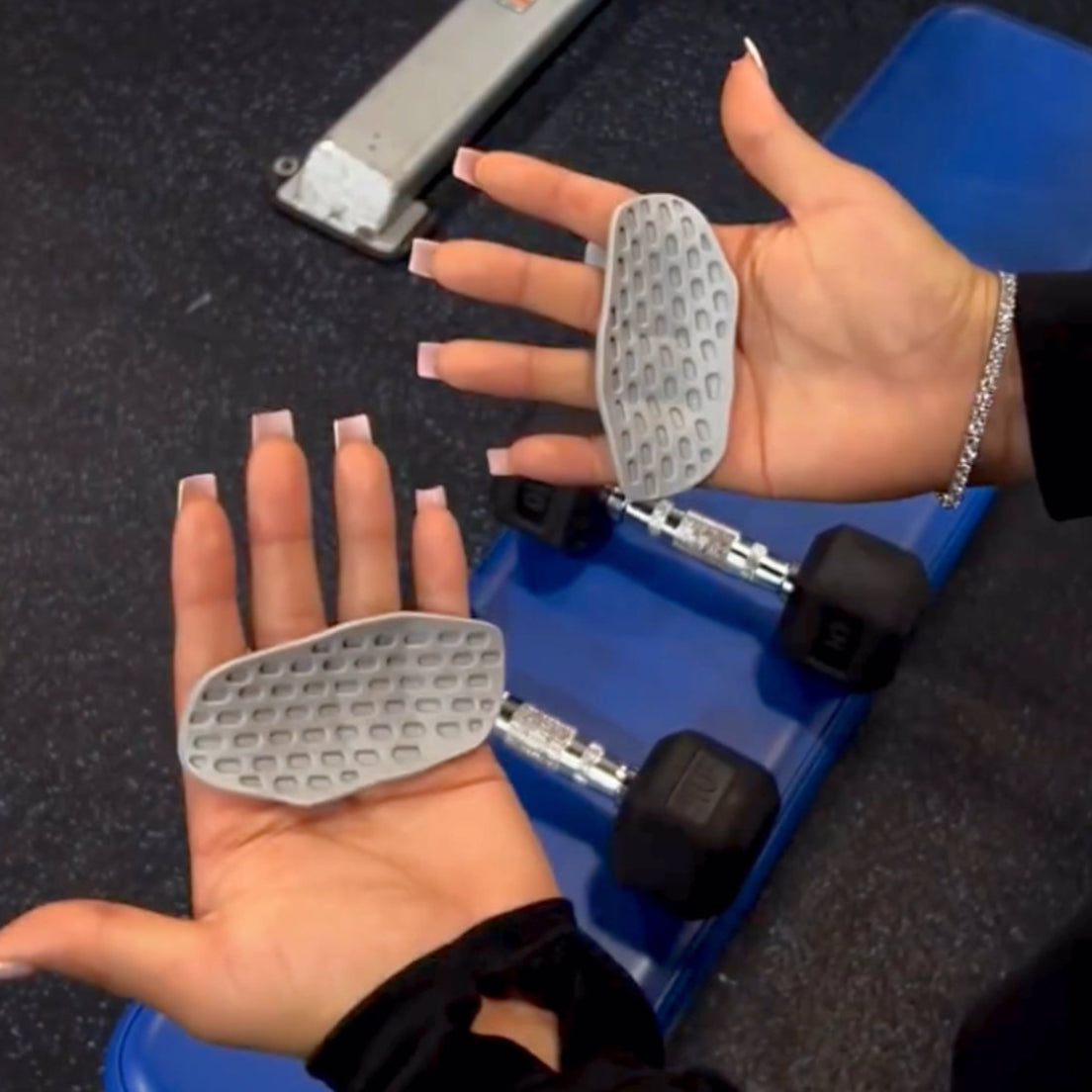 Hands holding gray workout hand pads grips