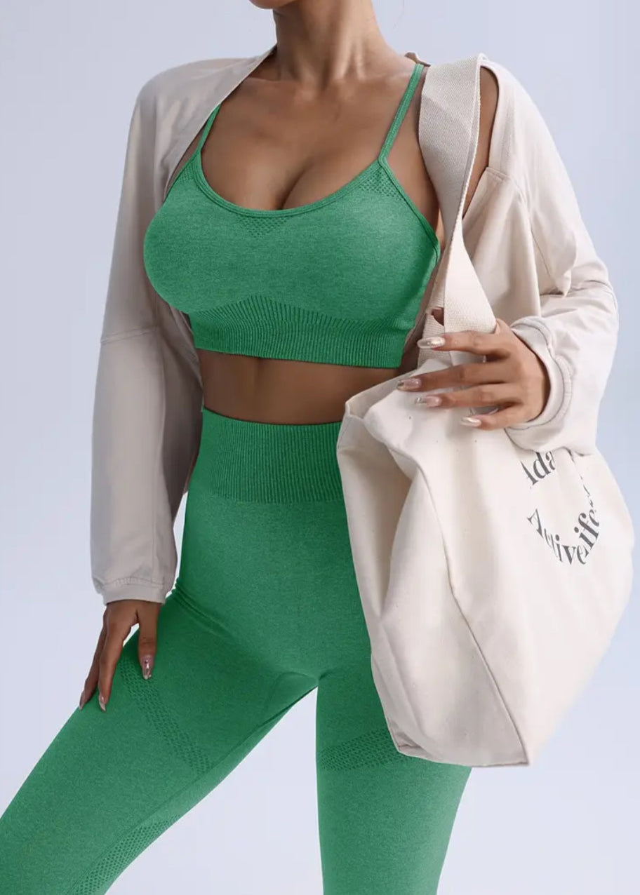 Person wearing a green sports bra and leggings with a white jacket on a light gray background